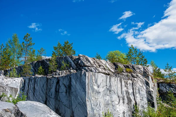 Terk edilmiş eski bir taş ocağında büyük gri taşlar. Mermer dokusu. Kayalıklarda pürüzsüz kesikler. Mermer ocağı yatay. Doğal taş. Mermer ocağı, vahşi mermer kayalar..