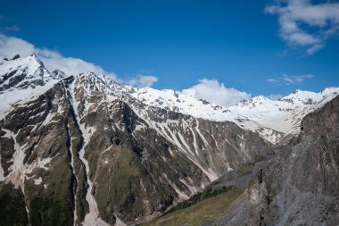 Dağ zirveleri karla kaplı mavi parlak gökyüzünün altında güzel bulutlar. Dünyanın güzel yerlerini keşfetmek için. Doğal manzara..