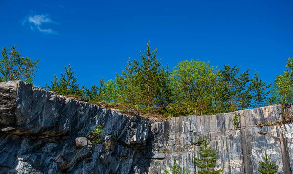 Terk edilmiş eski bir taş ocağında büyük gri taşlar. Mermer dokusu. Kayalıklarda pürüzsüz kesikler. Mermer ocağı yatay. Doğal taş. Mermer ocağı, vahşi mermer kayalar..