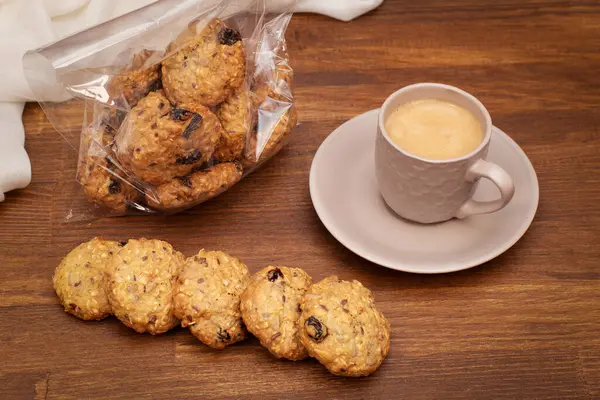 Tahta bir masada tahıllı ve kuru üzümlü lezzetli yulaf ezmeli kurabiyeler.