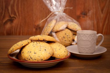 Yakın plan susam tohumlu ev yapımı bisküviler. Kahverengi ahşap arka planda bir fincan kahve ile tohum kurabiyeleri. Sağlıklı gıda konsepti. Boşluğu kopyala.