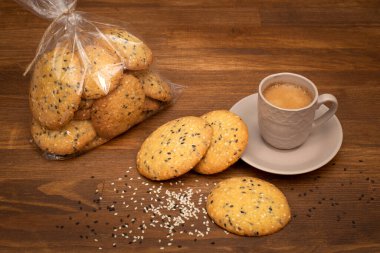 Kahverengi ahşap arka planda bir fincan kahveli susamlı kurabiye. Yakın plan ev yapımı kurabiyeler. Sağlıklı gıda konsepti. Uzayı kopyala Yukarıdan görüntüle