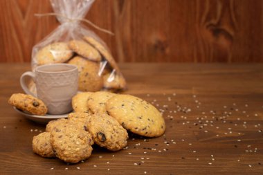 Ev yapımı tahıllı kurabiyeler, yulaf ezmesi, kuru üzüm, fındık, kahverengi ahşap arka planda tohumlar. Sağlıklı gıda konsepti. Boşluğu kopyala.