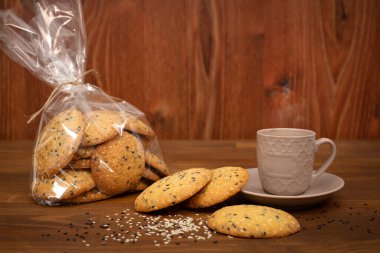 Yakın plan susam tohumlu ev yapımı bisküviler. Kahverengi ahşap arka planda bir fincan kahve ile tohum kurabiyeleri. Sağlıklı gıda konsepti. Boşluğu kopyala.