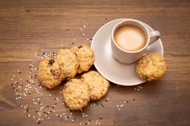 Bisküviler. Fındıklı ve mısır gevrekli yulaflı kurabiye. Kahverengi ahşap arka planda kurabiyeli bir fincan kahve. Sağlıklı yiyecekler. Kahvaltı tatlı konsepti. Yukarıdan görüntüle