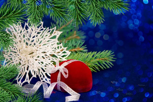 Yeni yıl kompozisyonu. Köknar dalları, mavi arka planda süslemeler için hediye kırmızı kutu. Noel, kış, yeni yıl konsepti. Boşluğu kopyala