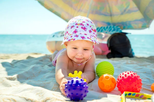 Bebek plajda oynuyor. Denizde bir çocuk. Kum ve su için oyuncaklar. Küçük çocuklar için güneş koruması.