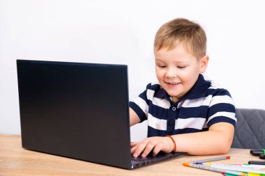 Mutlu çocuk bilgisayarda oynuyor. Çocuk ödevini tablet bilgisayarla yapıyor..