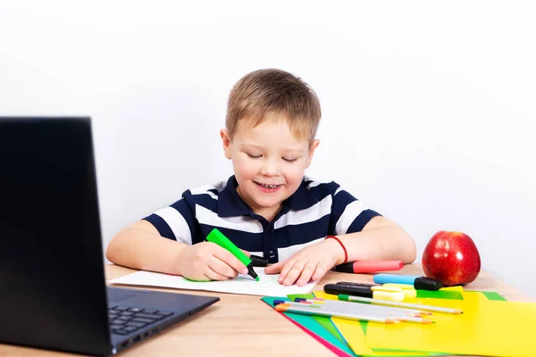 Okula dönelim. Küçük mutlu öğrenci masada resim çiziyor. Çocuk ödevini tablet bilgisayarla yapıyor..