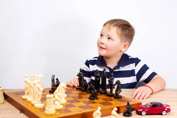 The boy plays chess. Children's chess. White background. Place to copy.