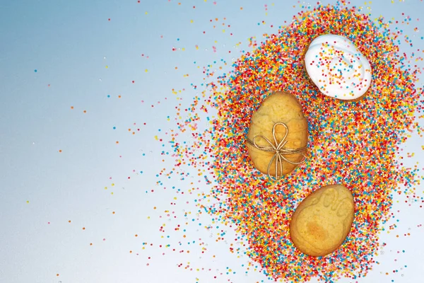 Mavi arka planda yumurtaları ve renkli serpintileri olan Paskalya çerçevesi. Pankart. Minimum konsept. Yukarıdan bak. Metin için kopyalama alanı olan kart.