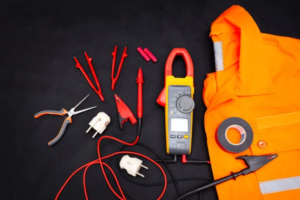 Profesyonel üniforma ve elektrikçi aletleri. Üniforma ve siyah arka planda bir takım aletler. İşçi Bayramı arkaplan kavramı.