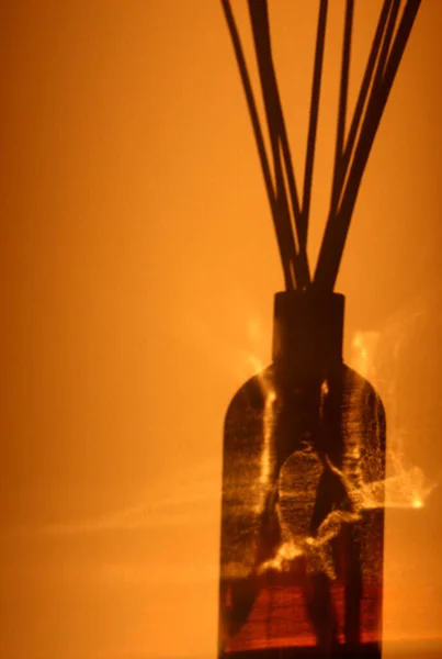Палочки ладана в стеклянной бутылке в оранжевой комнате, где дым окружает бутылку — стоковое фото