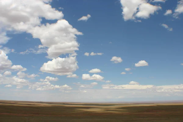 Panoramische opname van de blauwe New Mexico hemel met verspreide wolken over de vlakke woestijngrond — Stockfoto