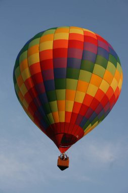Gökkuşağı kareli sıcak hava balonu bulutlu bir gökyüzünde uçuyor.