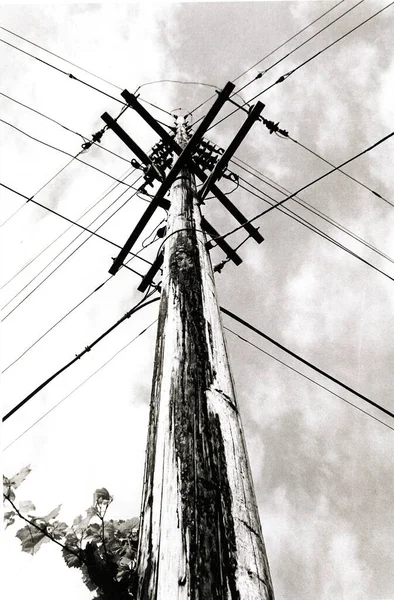 Vue des yeux vers en noir et blanc d'une vieille tige d'ancrage avec des lignes électriques croisées en forme de X — Photo