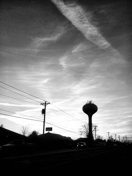 電話棒と水の塔黒と白の夕日の空にシルエット — ストック写真
