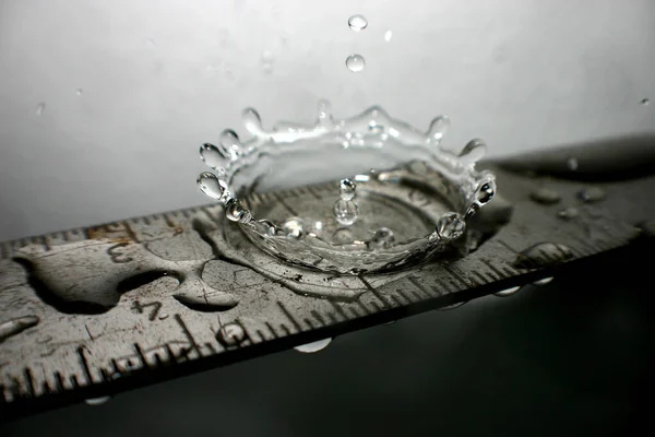 Wasser spritzt auf ein silbernes Lineal — Stockfoto