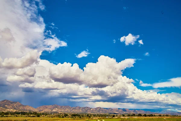 Nyílt kék ég viharfelhőkkel a sivatagi hegyek felé a horizont mentén. — Stock Fotó