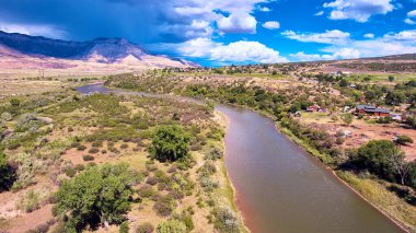 Dağları ve fırtına bulutları olan küçük çöl kasabasının yanındaki nehir.