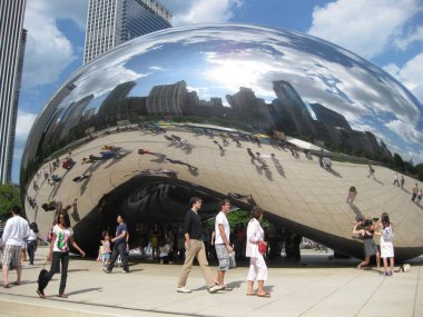 Chicago 'da birçok insan The Bean' in önünden geçiyor, bu da şehrin ufuk çizgisini yansıtıyor.
