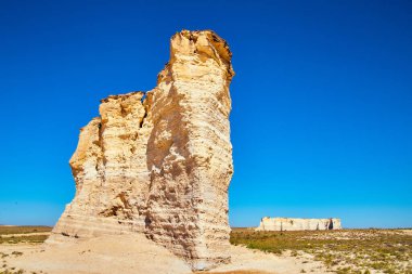 Büyük beyaz kaya sütunları düz çöl ve koyu mavi gökyüzünden sarkan