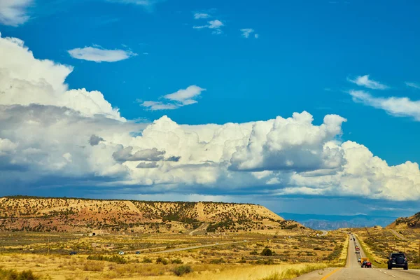 Wolken und blauer Himmel über Wüstenbergen und Autobahn mit Touristenautos — Stockfoto
