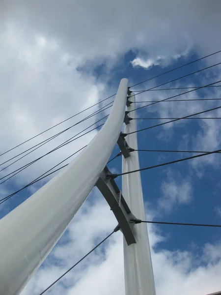 Wormser Blick auf eine weiße dreieckige Brücke mit Hängeseilen, die kreuz und quer durch einen blauen und bewölkten Himmel führen — Stockfoto