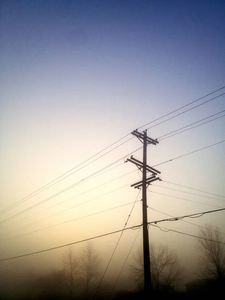 Hazy słup telefoniczny z drzew liściastych i szaroniebieskie niebo — Zdjęcie stockowe