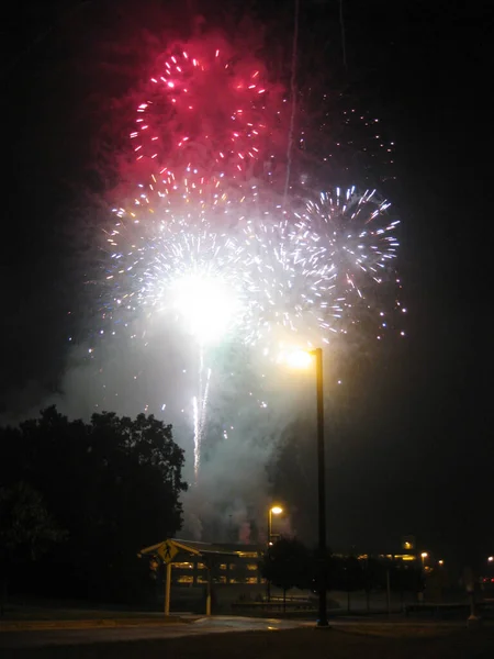 Alberi di silhouette di fuochi d'artificio bianchi e rossi e palo del telefono a tarda notte — Foto Stock