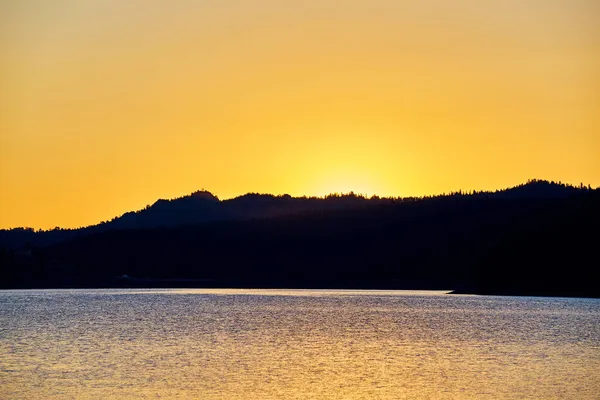 夕阳西下的落日，水面上，山的轮廓 — 图库照片