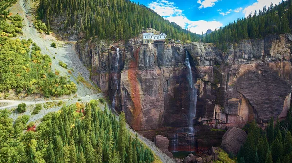 Grande cascata su centrale elettrica con scogliere e pini — Foto Stock