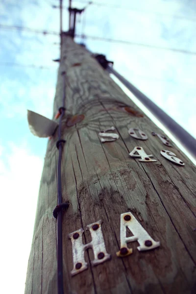 Large telephone pole with letters HA drilled into its side stretches towards the sky — Stock Photo, Image