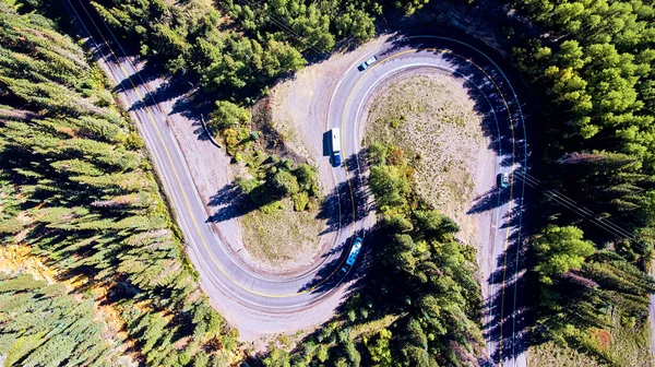 Road going down mountain aerial looking down with pine trees