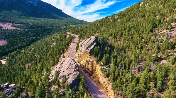 Estrada que corta através da rocha grande da montanha no vale dos pinheiros — Fotografia de Stock