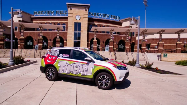 Carro branco com um envoltório que diz equipe de beisebol Tincaps com um estádio em segundo plano — Fotografia de Stock