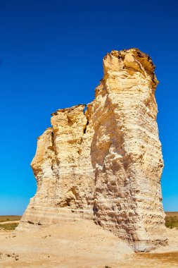 Düz çölden sarkan mavi gökyüzü ile beyaz kaya sütuna yakın.