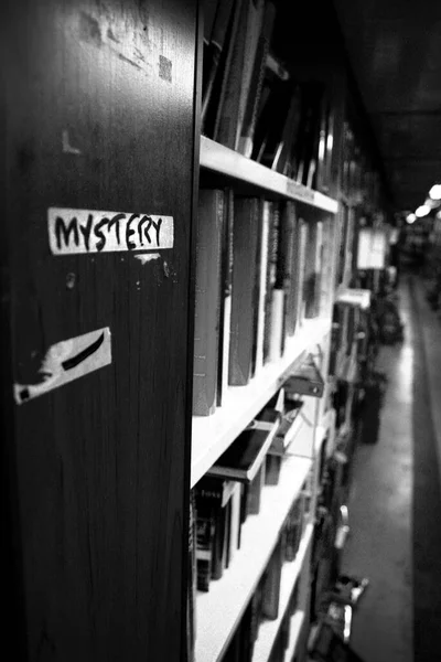 Schwarz-Weiß-Tiefenaufnahme einer Reihe von Büchern im Mystery-Bereich einer Bibliothek oder Buchhandlung — Stockfoto