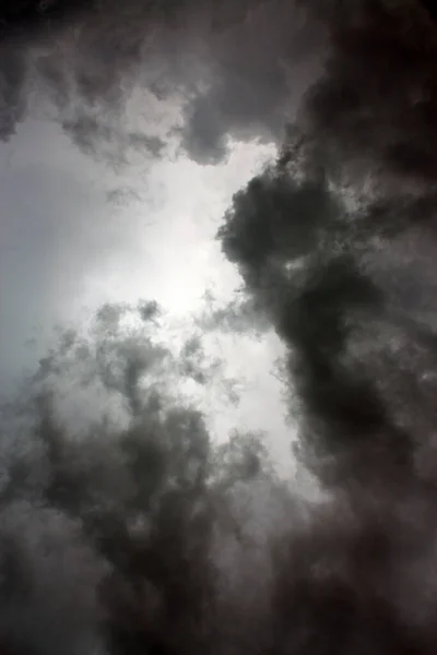 Δυσοίωνα μαύρα σύννεφα σχεδόν σβήνουν τον ήλιο που τα σιλουέτα — Φωτογραφία Αρχείου