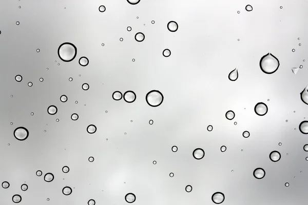 Vatten droppar mot ett glasfönster på en grå himmel — Stockfoto