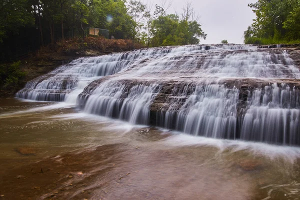 Hundratals kaskader vattenfall över sloppad sten i grön skog — Stockfoto