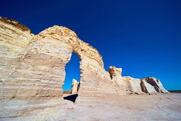 Kijkend naar witte pijlers van rots met boog en heldere blauwe lucht — Stockfoto