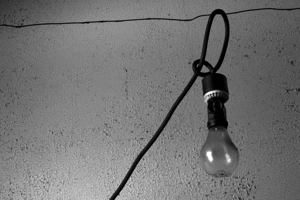 Svart och vitt foto av en exponerad glödlampa hängande från en tråd — Stockfoto