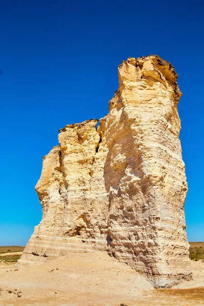 Düz çölden sarkan mavi gökyüzü ile beyaz kaya sütuna yakın.