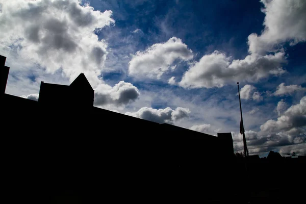 Grandes edificios y un asta de la bandera retroiluminados y siluetas contra un cielo parcialmente nublado — Foto de Stock