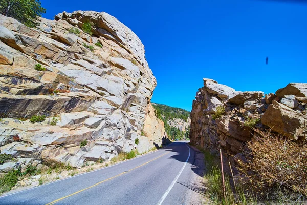 Estrada que atravessa montanha rochosa com grandes penhascos de rocha — Fotografia de Stock