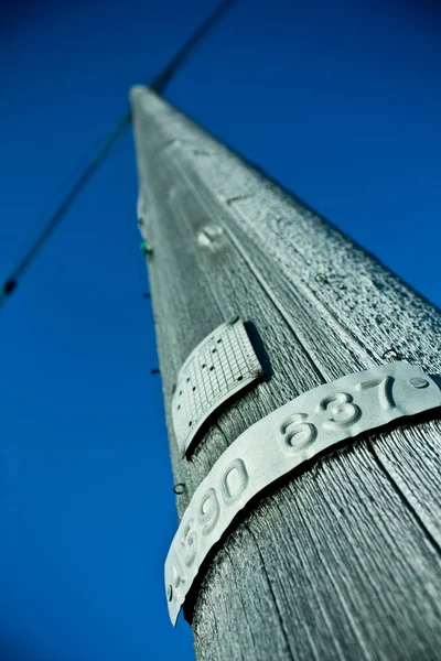 Smidig trä telefonstolpe med plack mot en blå himmel — Stockfoto