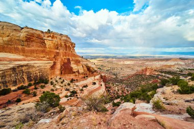Çöl kanyonunda geniş kırmızı uçurumlar açık vadi ve bulutlarla