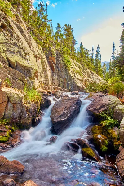 Verticaal van waterval door grote rotsblokken in bergen met korstmossen rotsen — Stockfoto