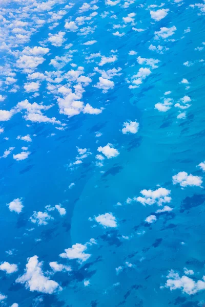 Dispersas pequeñas nubes blancas desde el avión proyectando sombras en el océano —  Fotos de Stock